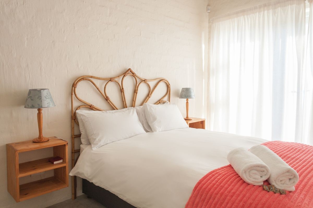 Clean and cozy white and cream bedroom of a holiday home, bed with white linen, folded towel and natural light Clean and cozy white and cream bedroom of a holiday home, bed with white linen, folded towel and natural light
